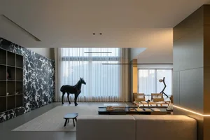 Modern minimalist living room with marble accent wall, large windows, and minimalist furniture.