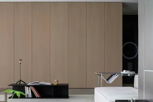 A minimalist living room with a white sofa, a black coffee table, and a large wooden cabinet in the background.