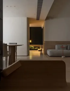 A minimalist living room with a wooden floor, concrete walls, and a cozy sofa.