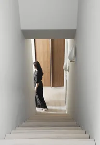 A minimalist living space featuring a wooden staircase with white walls and a wooden floor.