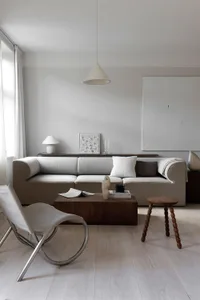 A minimalist living room with fabric sofa, wooden coffee table, and metallic chair.