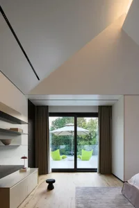 A modern bedroom with white cushions, wooden flooring, and floor-to-ceiling windows.
