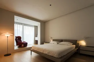 Modern minimalist bedroom with a neutral-toned color palette featuring a white bed.