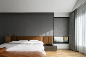 A modern bedroom with soft textiles on the bed, minimalist aesthetic, and natural light through the window.
