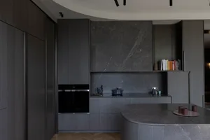 A modern kitchen featuring dark marble countertops and cabinets.