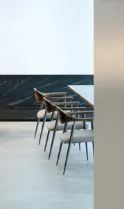 Modern interior design featuring wooden chairs with leather seats and metal legs.