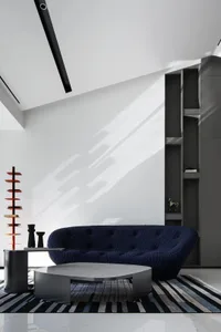 A modern living room featuring a textured cloth sofa and a geometric coffee table with a striped rug underneath.