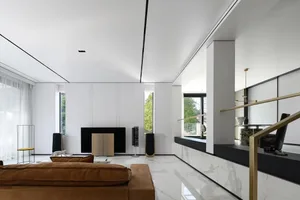 A modern, minimalist living room featuring white marble flooring and walls, a cozy brown sofa, and sleek, minimalist decor.
