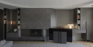 A modern living room featuring a marble fireplace, concrete floor, and metal accents.