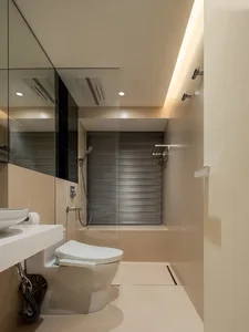 Modern bathroom with white fixtures, beige walls, and a walk-in shower.
