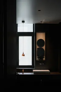 A modern minimalist bathroom with a glass wall and metallic accents.