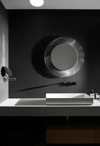 Modern minimalist bathroom with a black metallic mirror and a sleek white sink.