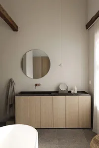 Modern minimalist bathroom with a wooden vanity and a black stone countertop.