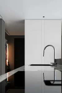 Modern minimalist kitchen with a marble countertop and stainless steel faucet.