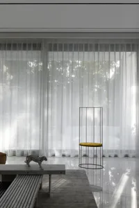 A minimalist living room with glass, marble, and metal elements.