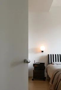 A modern bedroom featuring a black and white striped headboard and a sleek, metallic bedside table with drawers.