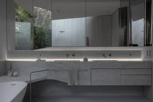Modern minimalist bathroom featuring white marble surfaces and sleek design elements.