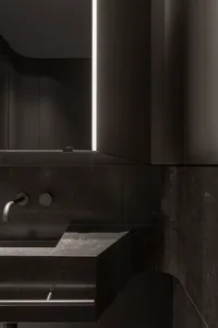 A modern bathroom with black marble surfaces and minimalist design.