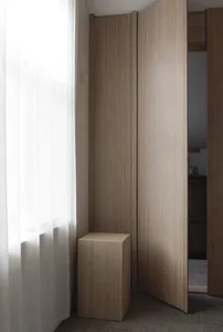 A modern closet with wooden folding doors, open to reveal a minimalist interior.