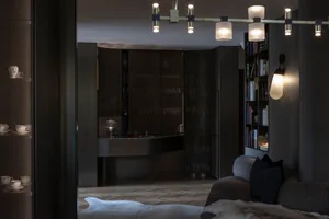 A modern dark-themed interior featuring a living room and bar area with dark wooden finishes and minimalistic design elements