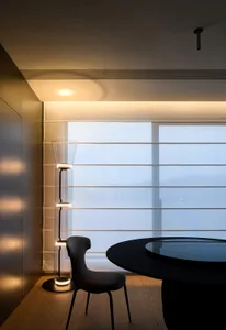 A modern dining room featuring sleek, glass furniture and a round table.