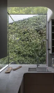 A modern kitchen featuring a glass window overlooking lush greenery.