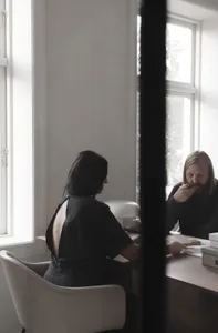Two individuals engaged in a meeting within a modern office setting.