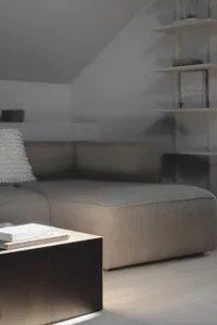 A modern minimalist living room features a grey sofa with textured fabric, a wooden coffee table, and white shelves in the ba