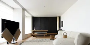 A modern living room with a white sofa and wooden dining table and bench.