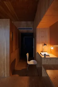 A minimalist residential room with wooden walls, flooring, and furniture.