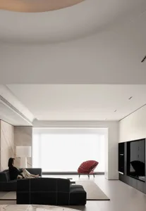 A modern living room with a black sofa, a red chair, and a large window.