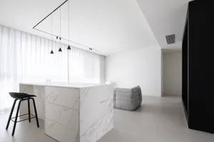 A modern minimalist lounge area with marble flooring and furniture.