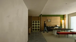 A modern living room with a concrete floor, green accent wall, and wooden furniture.