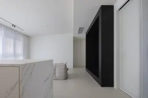 Modern minimalist living room with a white marble countertop and black walls.
