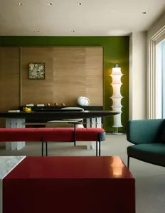 Modern living room with a red upholstered bench, green and brown walls, and a green sofa.