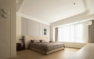 A minimalist modern bedroom featuring a beige bed with matching beige bedding and curtains.