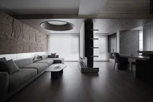 A modern living room with a stone accent wall, wooden accents, and glass elements.