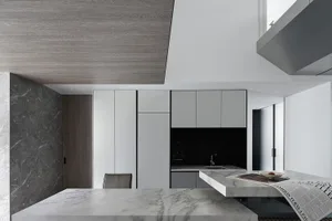 A modern kitchen interior with marble countertops and concrete elements.