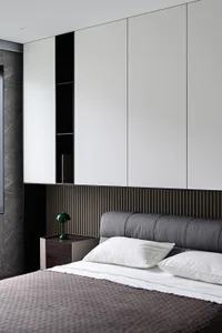 Modern minimalist bedroom with a wooden headboard and white bedding.
