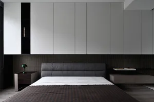 A modern bedroom featuring a bed with textured fabric headboard and wooden floor.