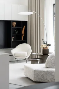 A minimalist living room with a modern armchair in velvet, a sleek floor lamp, and a cozy ottoman against a backdrop of a lar