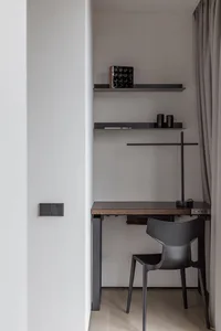 A minimalist workspace featuring a wooden desk and a metal chair.