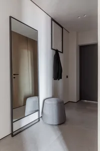 Modern minimalist entrance hall with a large mirror, upholstered stool, and minimalist coat hanger.