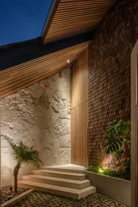 Modern concrete, wood, and stone entrance with steps, lighting, and potted plant