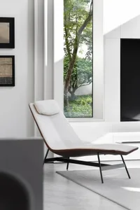 Modern living room with white fabric chaise longue, minimalist decor, and large window overlooking greenery.