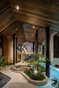 Modern living room with wood ceilings, concrete seating area, and glass walls.