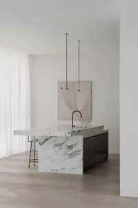 Modern kitchen with white marble countertops and black cabinetry.