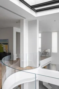 Modern residential interior design featuring glass railings and white walls.