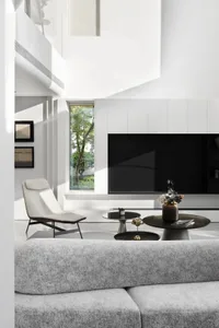 A modern minimalist living room with light-colored furniture, a sleek black entertainment center, and a neutral color palette