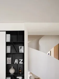 White staircase with black railings and minimalist decor in a modern interior design setting.